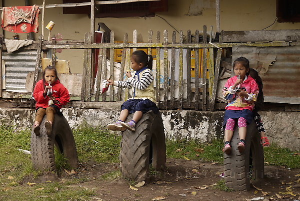 Three Little Schoolgirls Sitting On Three Heavy Truck Tires